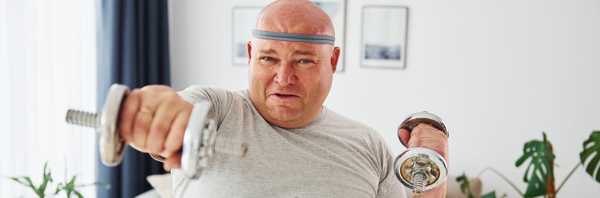 Ein &uuml;bergewichtiger Mann treibt zu Hause Sport