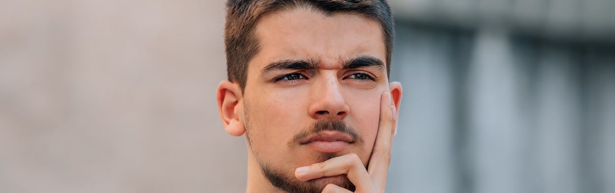 Junger Mann, der mit einer st&ouml;renden Frage besch&auml;ftigt aussieht
