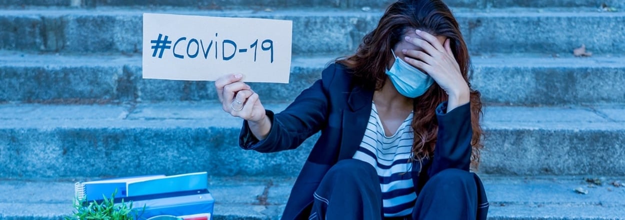 Traurige Frau mit Gesichtsmaske, die eine Kiste mit Personal und einem COVID-19-Schild in der Hand h&auml;lt