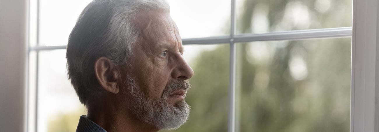 Ungl&uuml;cklicher Senior, der durch das Fenster schaut