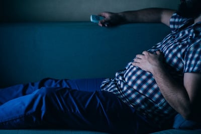 Ein Mann liegt auf der Sofa mit der Fernbedienung