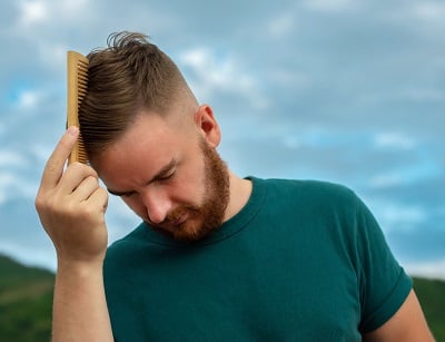 Ein Mann k&auml;mmt sein Haar mit einem Kamm.