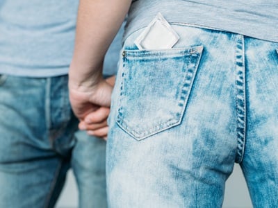 Ein Paar h&auml;lt sich an den H&auml;nden, mit einem Kondom in der Jeanstasche