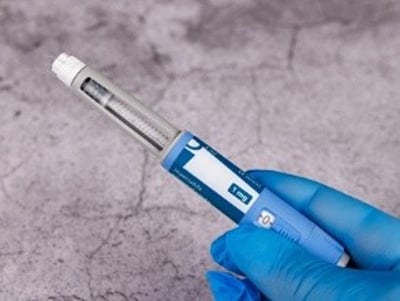 H&aring;nd med bl&aring; handsker holder semaglutid-pen