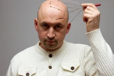Um homem a massajar o couro cabeludo.