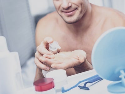 Ein Mann tr&auml;gt in einem Badezimmer Hautpflege- und Hygieneseife auf